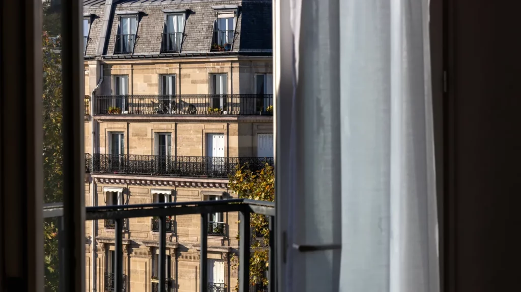 Fenêtre ouverte sur une façade haussmannienne à Paris, lumière du matin